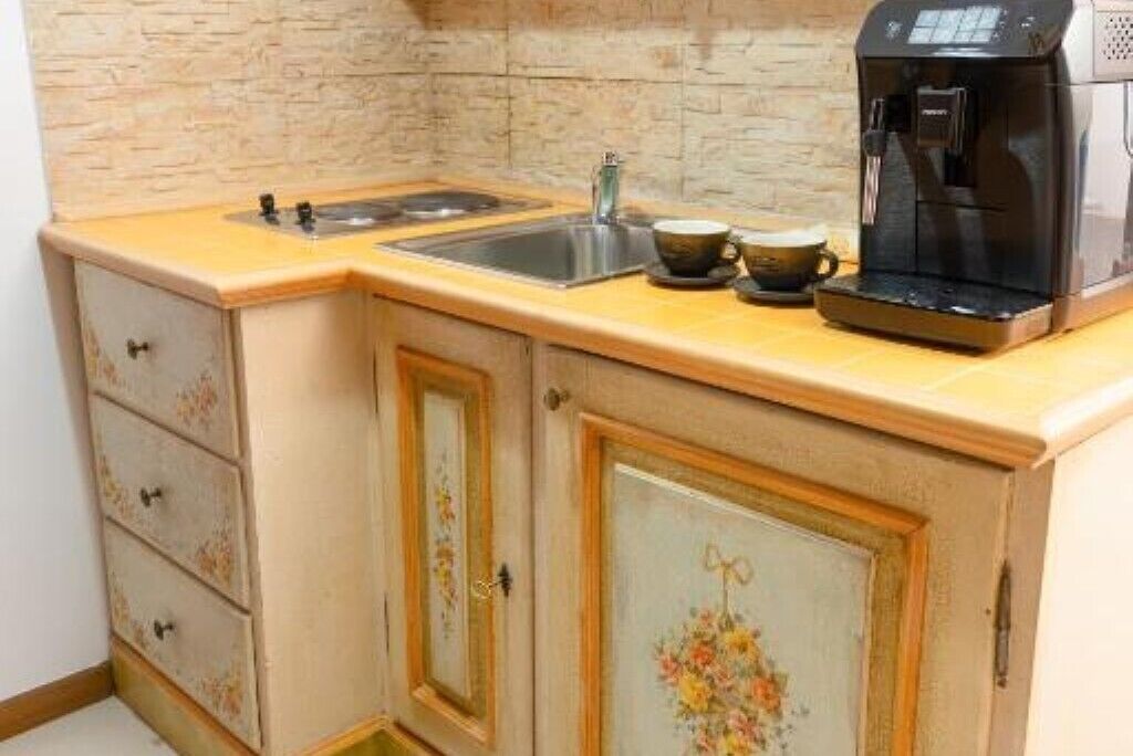 A kitchen with a coffee maker, two cups, and a sink.