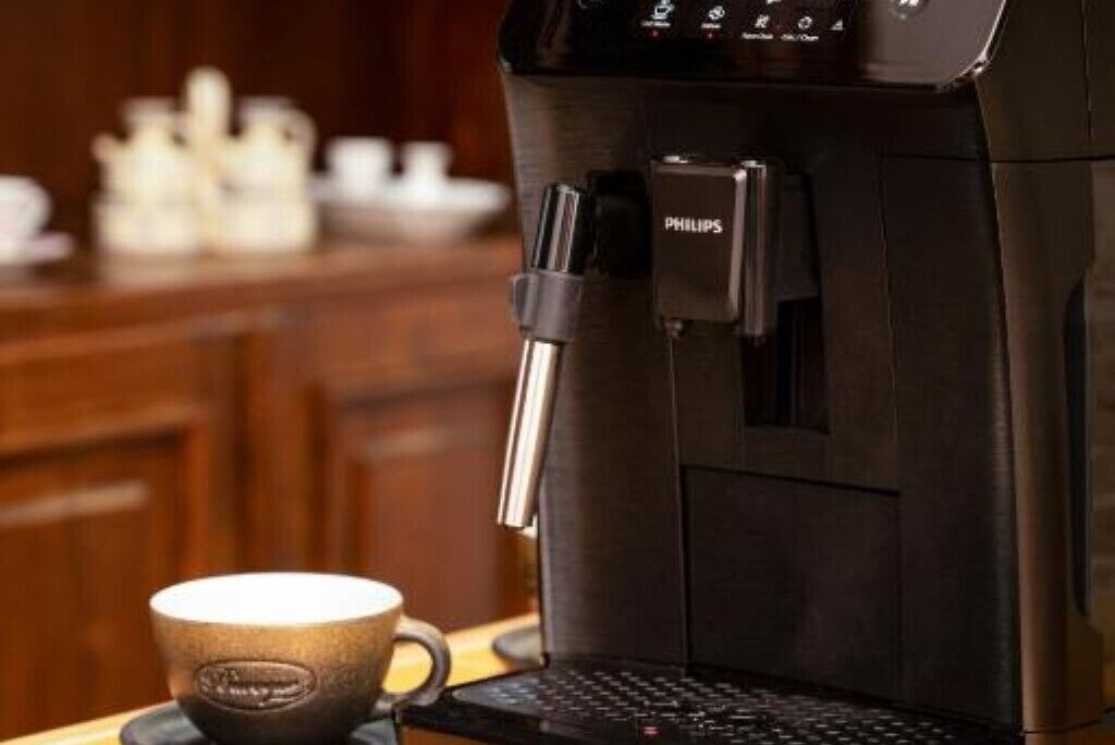 A coffee machine with a water reservoir and a coffee cup on a table.