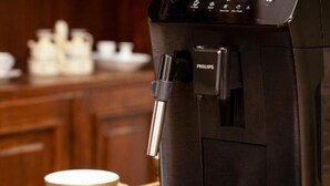 A coffee machine with a water reservoir and a coffee cup on a table. - Apartament 8 (Timișoara)