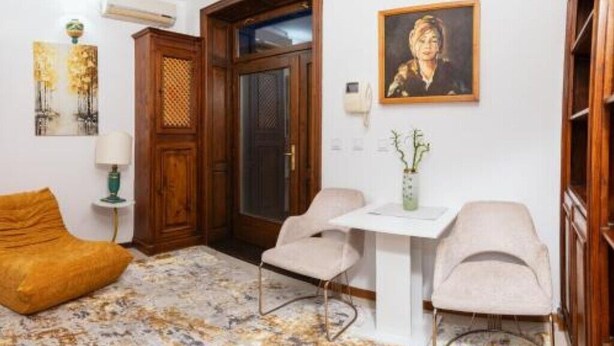 A room with a wooden door, a white table with chairs, a sofa, and a painting on the wall. - Apartament 8 (Timișoara)