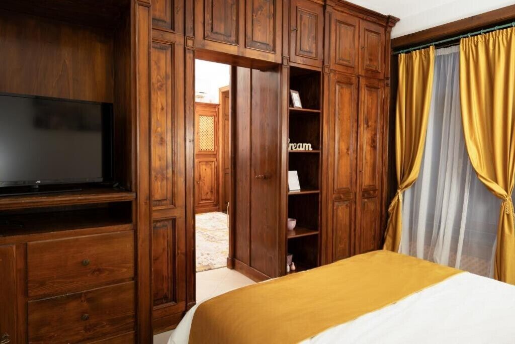 A room with a bed, wooden wardrobe, and a television.