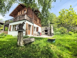 A rustic wooden building with a balcony, stone fireplace, and a stone sculpture in the foreground. - Beautiful private villa for 8 guests with WIFI, TV, terrace and panoramic view (Vercorin)