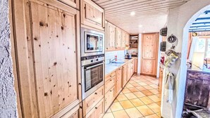 Una cocina con armarios de madera, horno empotrado y piso de baldosas.