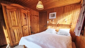 Una habitación de madera con una cama, una silla y un armario de madera.