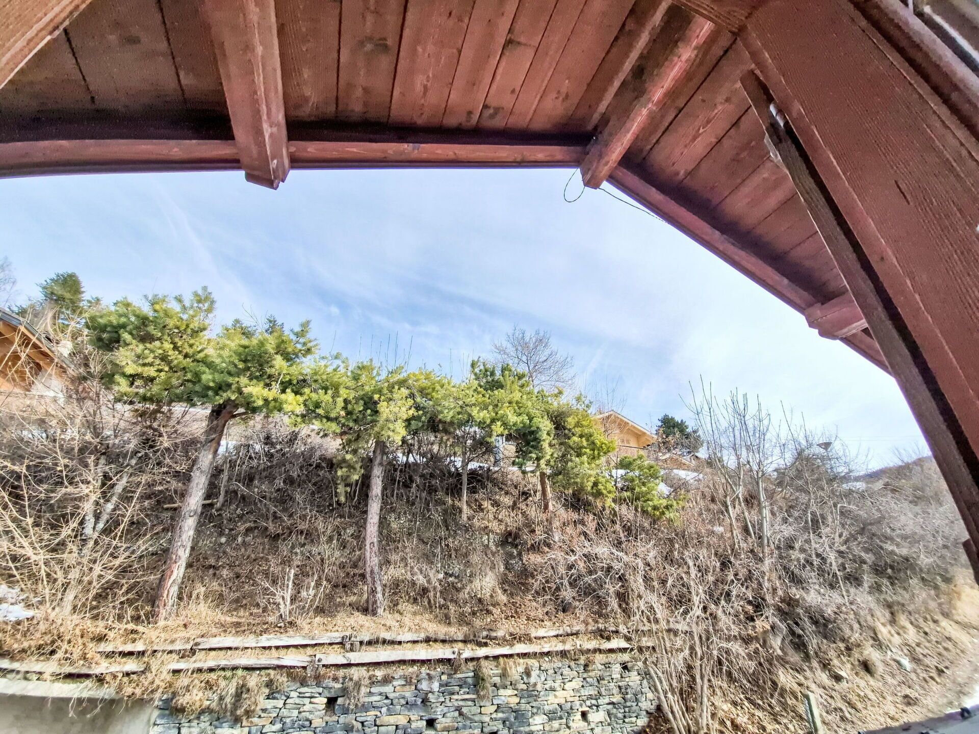 Una estructura de madera con un sendero de piedra que conduce a una masa de agua, rodeada de árboles y vegetación.