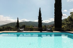 A swimming pool with a wooden fence, two bean bags, and tall trees. - Stunning private villa with private pool, A/C, WIFI, TV, patio and panoramic view, close to Cort... (Lisciano Niccone)