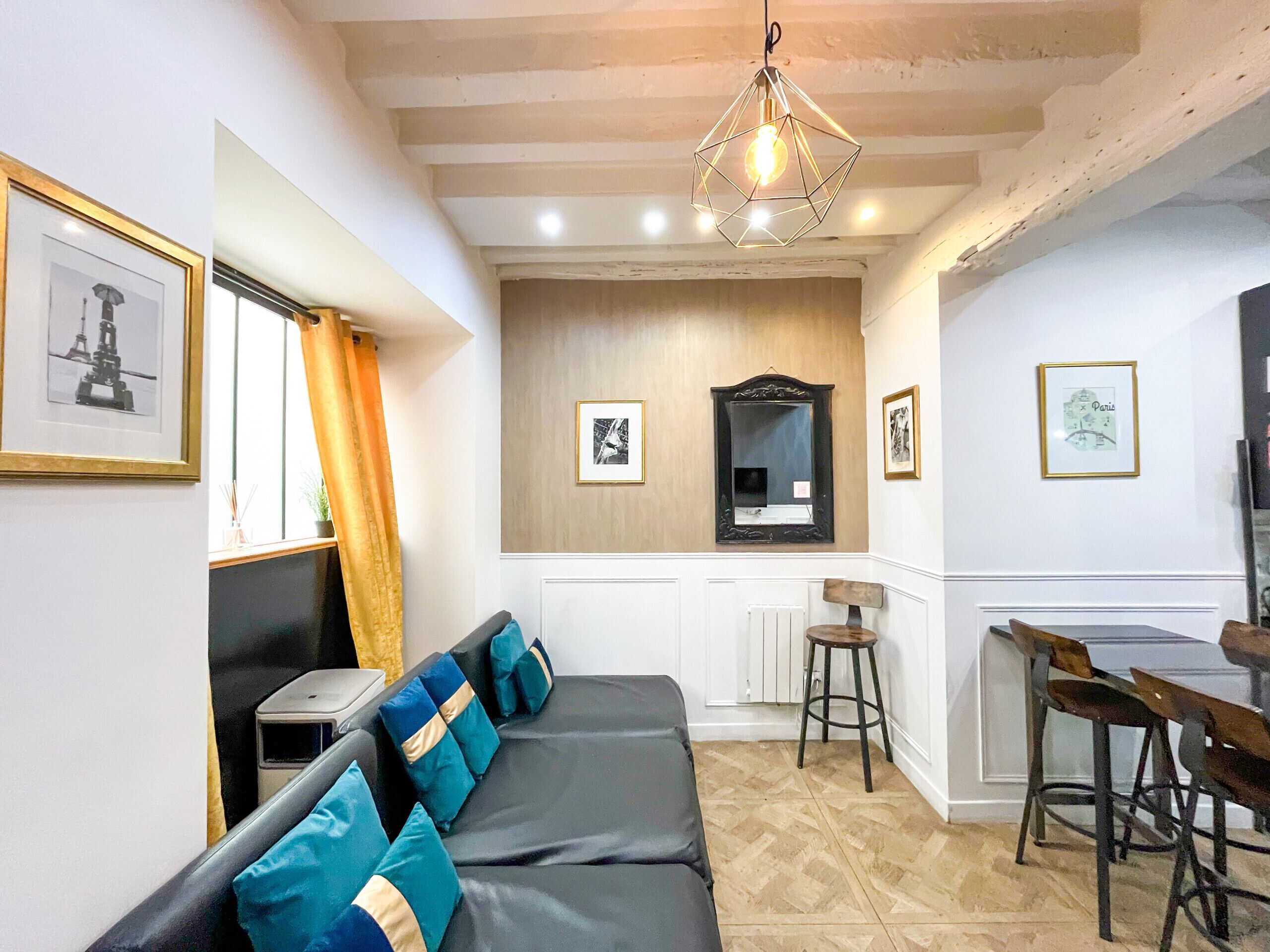 Una habitación con un sofá, una mesa de comedor, un espejo y cuadros en las paredes.