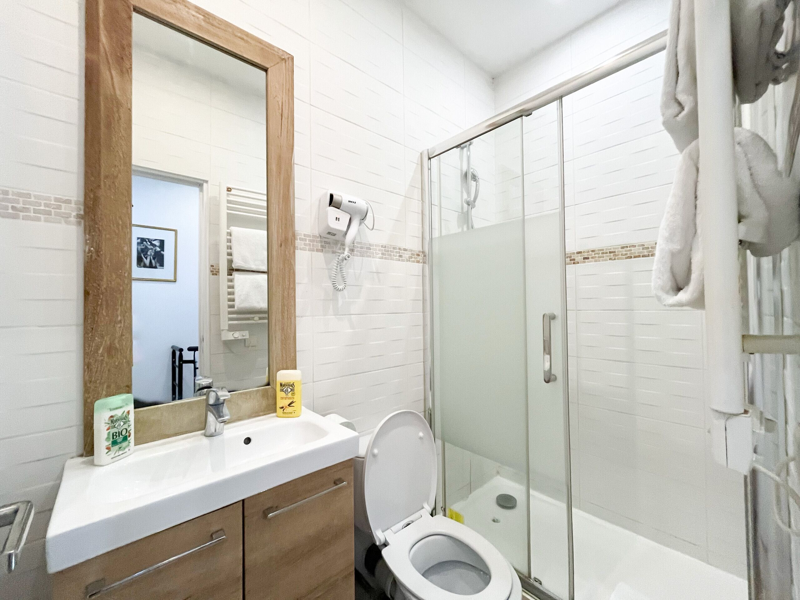 A bathroom with a white sink, a mirror, a toilet, and a glass shower enclosure.