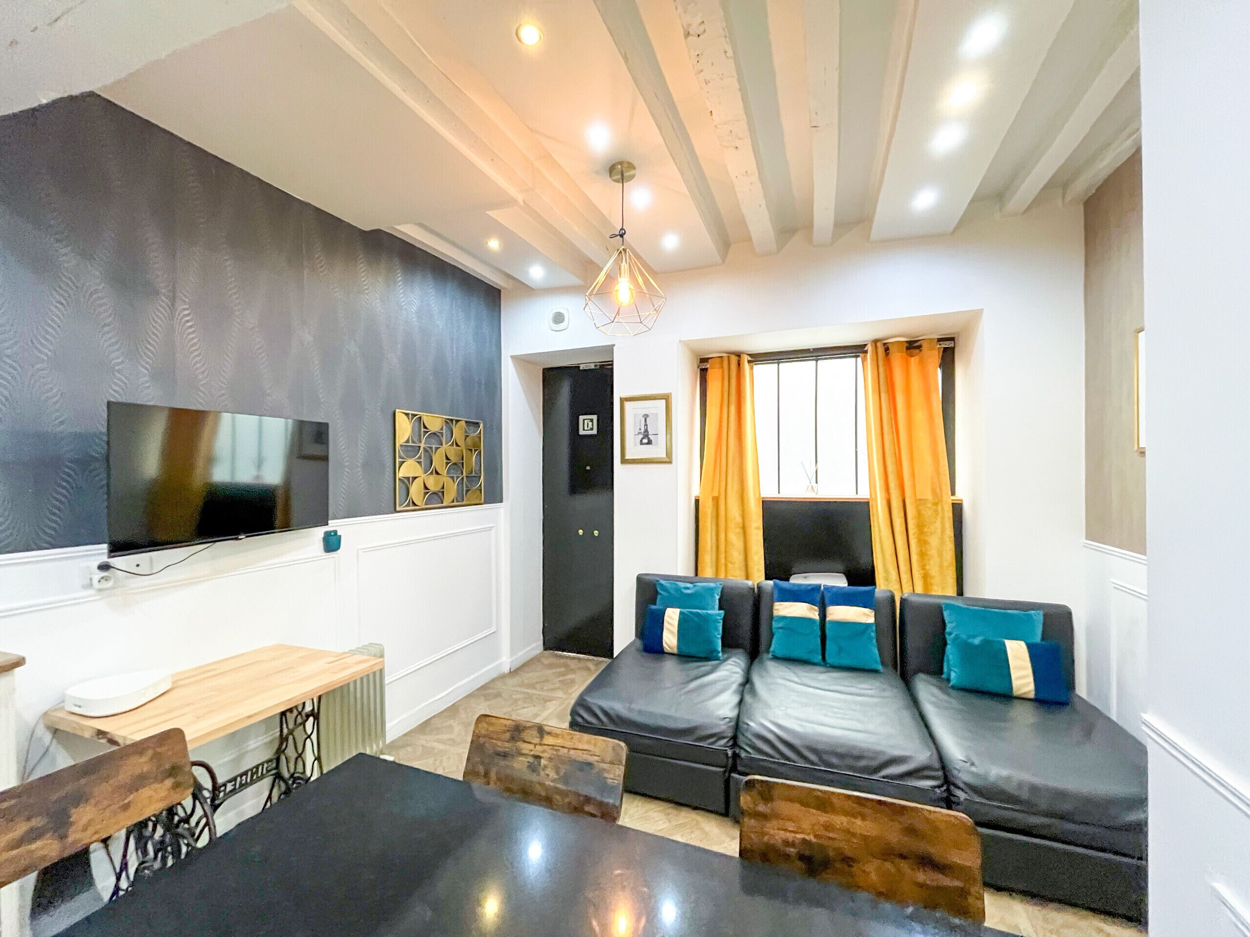 A living room with a sofa, television, table, and a dining area with chairs.
