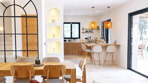 Een moderne woonkamer met een rode bank, een eethoek en een keuken op de achtergrond.