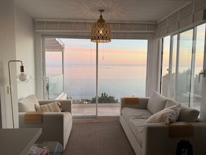 Una sala de estar moderna con dos sofás, una mesa de centro y un gran ventanal con vista al mar.
