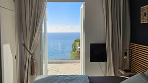 Un dormitorio con cama, televisor y vista al mar.