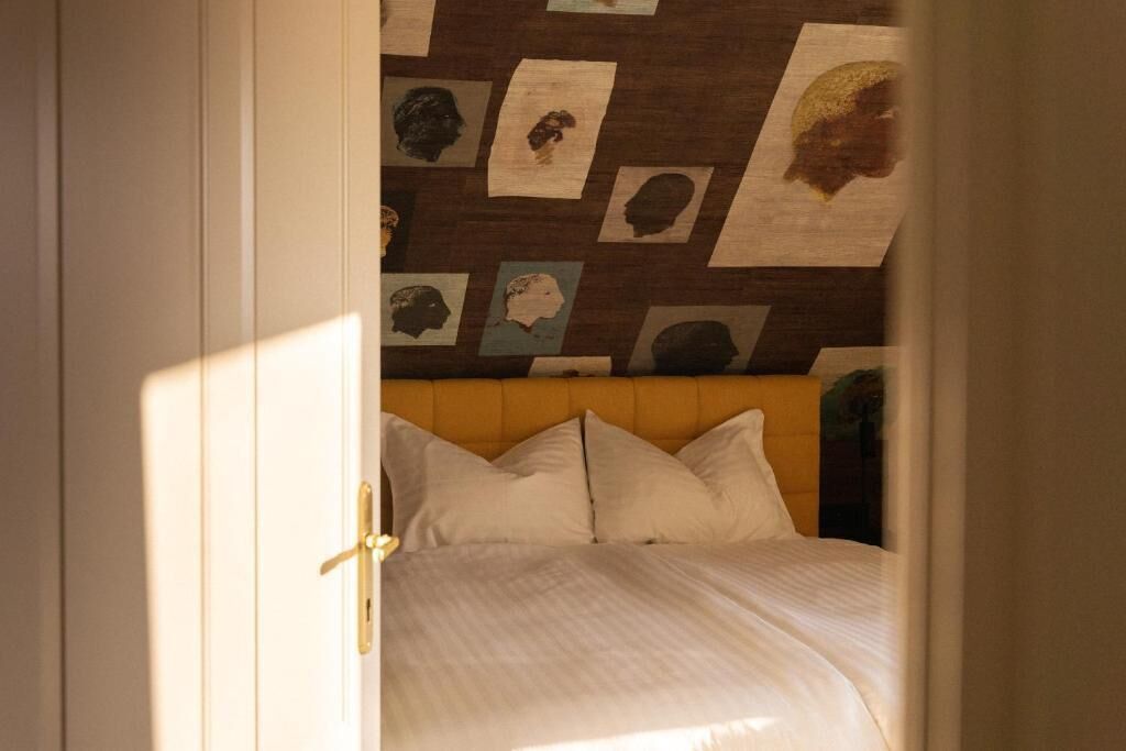 Una camera da letto con un letto, una testiera e una parete decorata con diverse foto incorniciate.