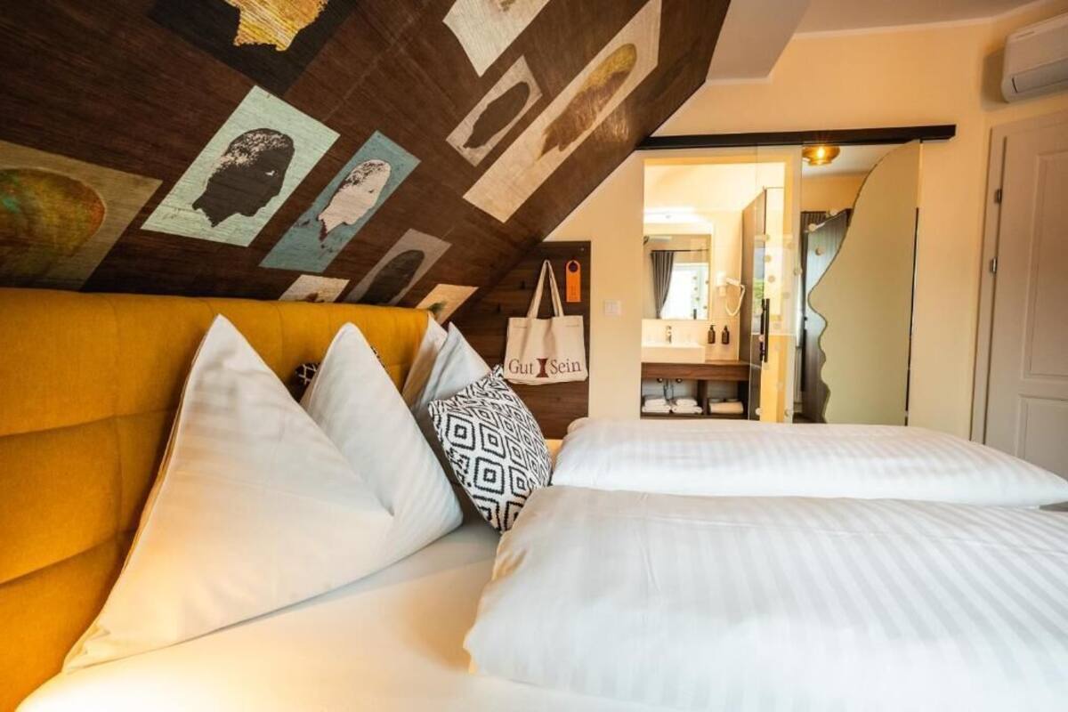 Een hotelkamer met een bed, een geel hoofdeinde en een plafond met kunstwerk.