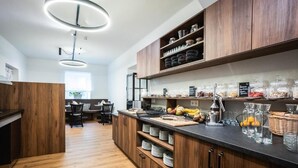 A modern kitchen with wooden cabinets, a central island, and a breakfast bar. - Hotel Gut Sein  (Sankt Georgen im Lavanttal)