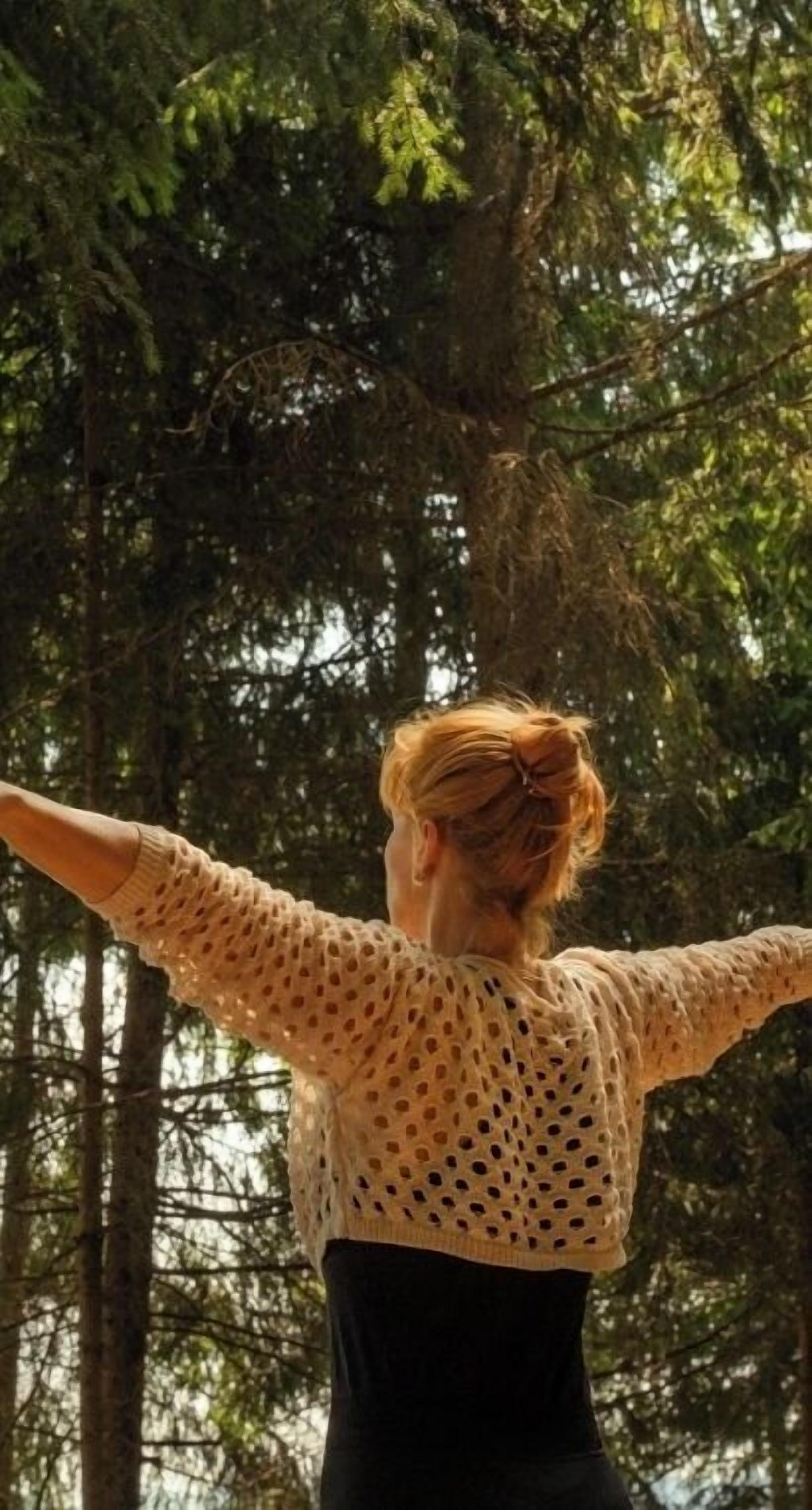 Una persona de pie con los brazos extendidos en un bosque.