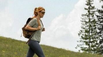 A person walking in a grassy field with a backpack.