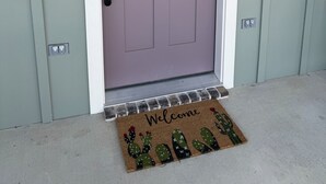 A door with a window, a doormat with cacti, and a mailbox. - ✪ Armadillo Rodeo ✪ 1 mile to Baylor, 1/2 mile to Magnolia Silos! (Waco)