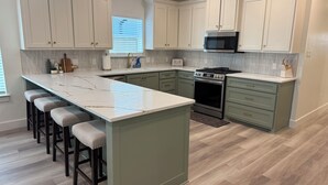 A kitchen with a central island, bar stools, a microwave, and a stove. - ✪ Armadillo Rodeo ✪ 1 mile to Baylor, 1/2 mile to Magnolia Silos! (Waco)