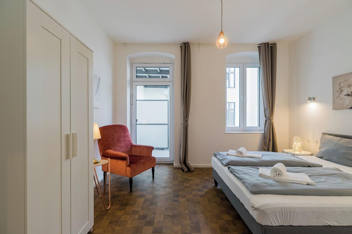 Un dormitorio con cama, una silla, un escritorio y una ventana.