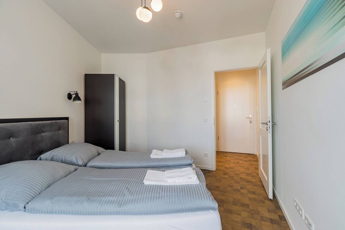 Un dormitorio con dos camas, un armario y una puerta que da a otra habitación.