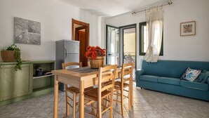 Ein kompakter Wohnraum mit Essbereich, einer Küchenzeile, einer Couch und einem Balkon.