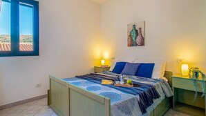 Ein Schlafzimmer mit einem Bett, zwei Nachttischen, einem Fenster und einem Bild an der Wand.