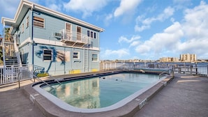 Un espace piscine offrant une vue dégagée sur la piscine, un bâtiment doté d’un balcon et un paysage urbain en arrière-plan.