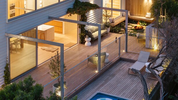 A modern house with a large glass window, a wooden deck, a swimming pool, and a fire pit. - Bridgewater House Gas Heated Pool (Melbourne)