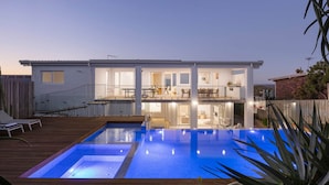 Ein zweistöckiges Haus mit Schwimmbad, Balkon und umzäunter Garten.