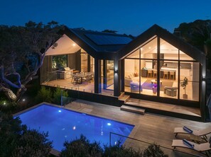 Une maison moderne dotée d’une piscine, de grandes baies vitrées et d’une terrasse.