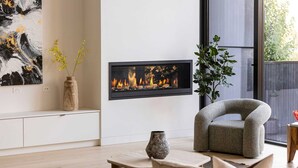 Een moderne woonkamer met een open haard, een bank, een salontafel en een plant.