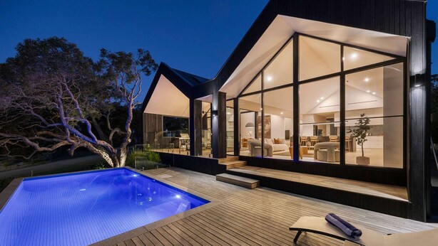 Een modern huis met zwembad, grote ramen en een terras.
