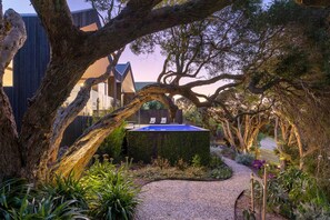 Un bâtiment moderne doté d’une piscine, entouré d’arbres et bordé d’un chemin de gravier.