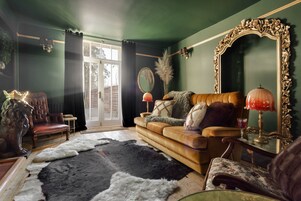 A room with a leather sofa, a large mirror, and a patterned rug.