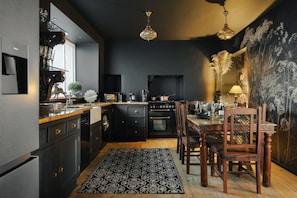 Una cocina moderna con muebles oscuros, una mesa de comedor de madera y una araña.