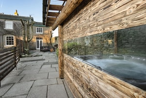 A spa area with a hot tub, stone walls, and wooden paneling.