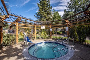 A hot tub area with a wooden pergola, a pool, and surrounding greenery. - Lake Forest Glen #142 by Hauserman Rentals (Tahoe City)