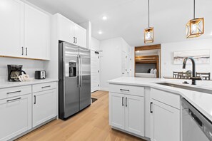 A modern kitchen with white cabinets, stainless steel appliances, and pendant lighting. - Keystone Condo With Pool (Keystone)