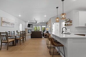 A modern kitchen with white cabinetry, a central island, bar stools, and pendant lighting. - Keystone Condo With Pool (Keystone)