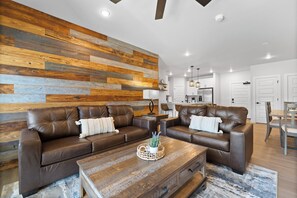 A modern living room with two brown leather sofas, a wooden coffee table, and a wooden wall panel. - Keystone Condo With Pool (Keystone)