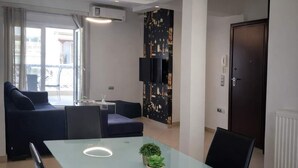 A modern living room with a glass table, black chairs, a sofa, and a TV. - Faliro Escape - Spacious Stay in Thessaloniki (Thessaloniki)