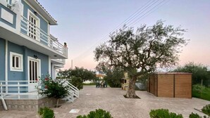 Un edificio con balcón, un árbol y plantas en macetas.