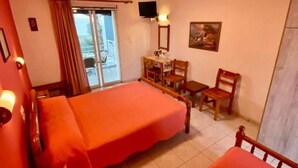 Habitación de hotel con dos camas, un escritorio, una silla, un televisor y una ventana con cortinas.