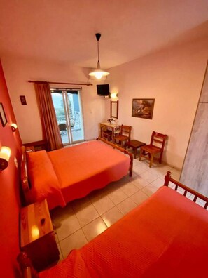 Ein Hotelzimmer mit zwei Betten, einem Schreibtisch, einem Sessel, einem Fernseher und einem Bild an der Wand.
