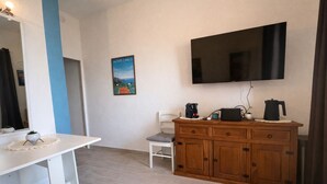 A small room with a white desk, a chair, a wooden cabinet, a flat-screen TV, and a poster on the wall. - T2 balcony with barbecue, Tennis MC (Beausoleil)