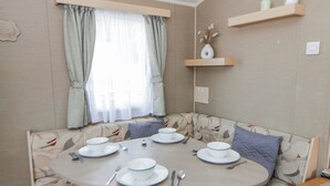Zona pranzo con tavolo rotondo apparecchiato per quattro persone, circondata da divani con motivi decorativi.