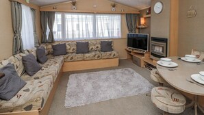 Un interno camper accogliente con divano, televisore, camino, tavolo da pranzo e tende.