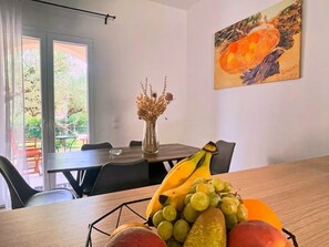 Ein Essbereich mit einem Tisch für zwei Personen, einer Vase mit getrockneten Blumen und einem Bild an der Wand.