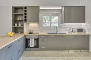 Eine moderne Küche mit grauen Schränken, einer Holz Arbeitsplatte, einem eingebauten Ofen und einem Fenster über der Spüle.